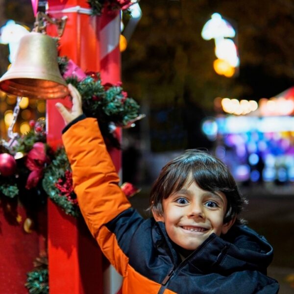Bambino felice suona la campanella al Mercatino di Natale di Verona